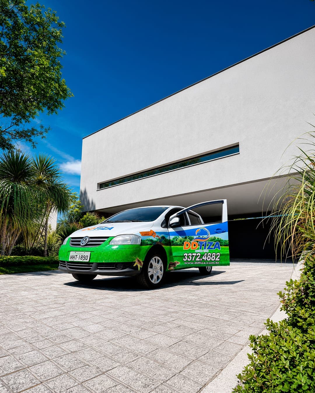 Veículo da DDTIZA com identificação e telefone, estacionado na entrada de um imóvel em Belo Horizonte